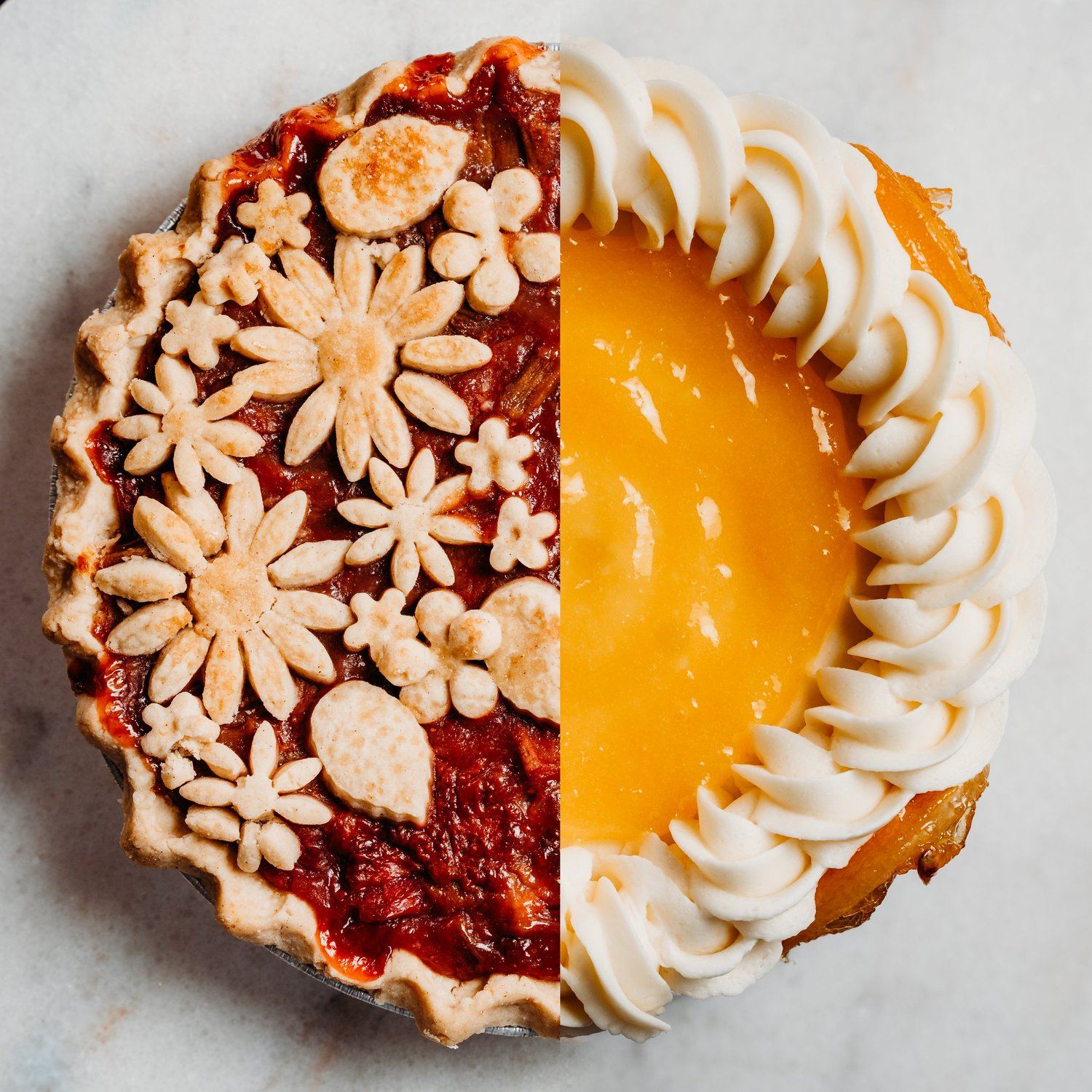 A pie that is half berry with pastry flowers and half lemon with cream